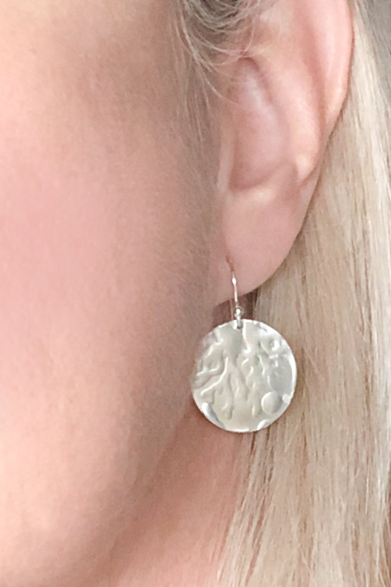 silver round earrings with coral texture on model